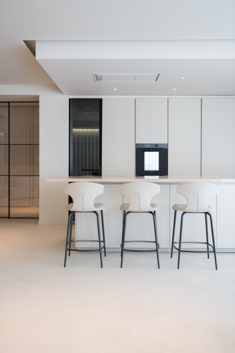 cucina a isola poliform chiara nel living di un attico con dettagli in travertino