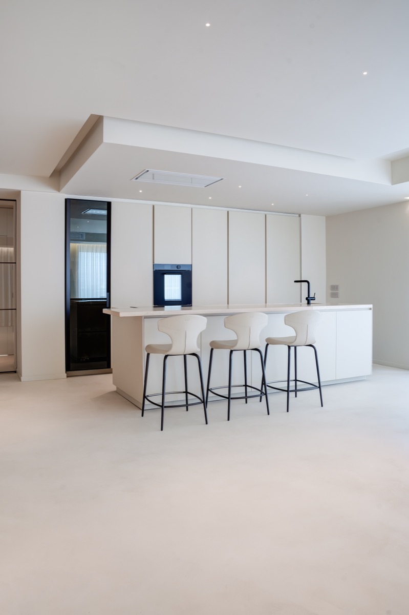 cucina a isola poliform chiara nel living di un attico con dettagli in travertino