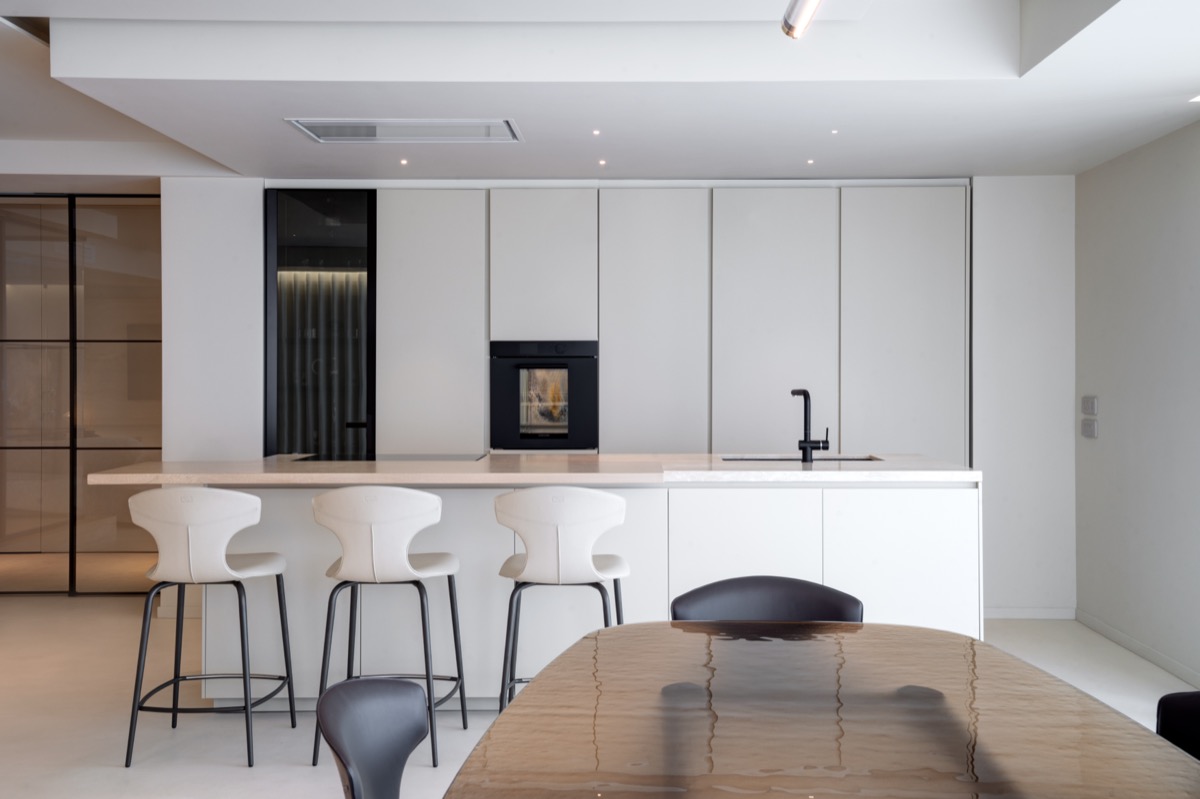 cucina a isola poliform chiara nel living di un attico con dettagli in travertino