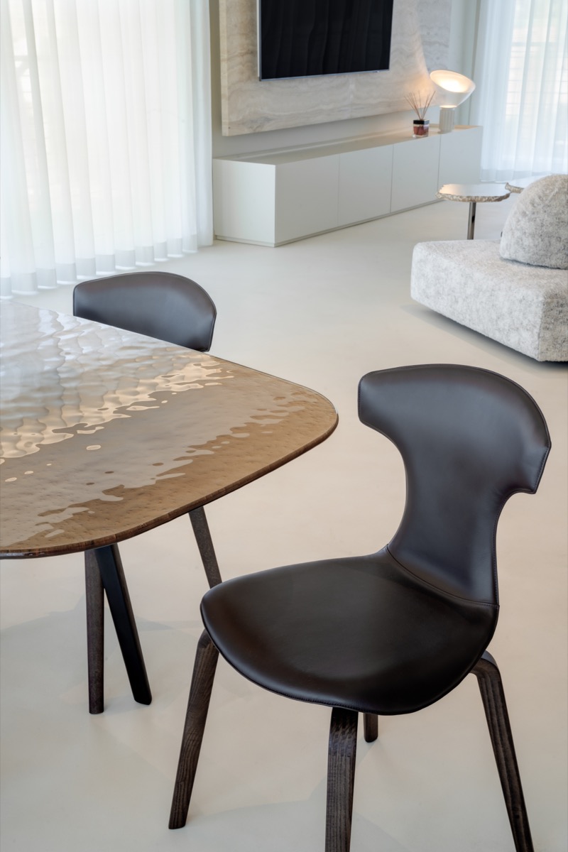 sala da pranzo con tavolo fiam e sedie frau nel living di una casa con eleganti finiture in travertino