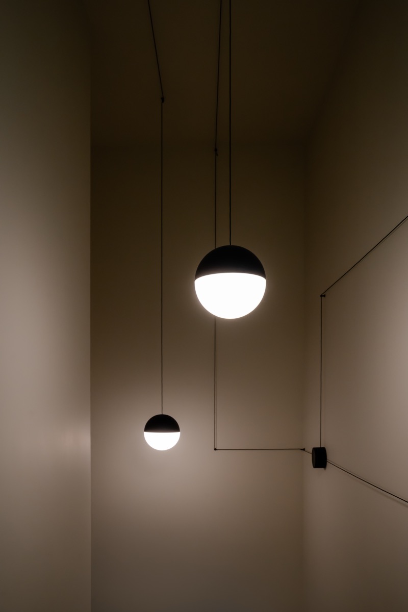 sistema di illuminazione con lampade flos su misura per un elegante appartamento con finiture in travertino