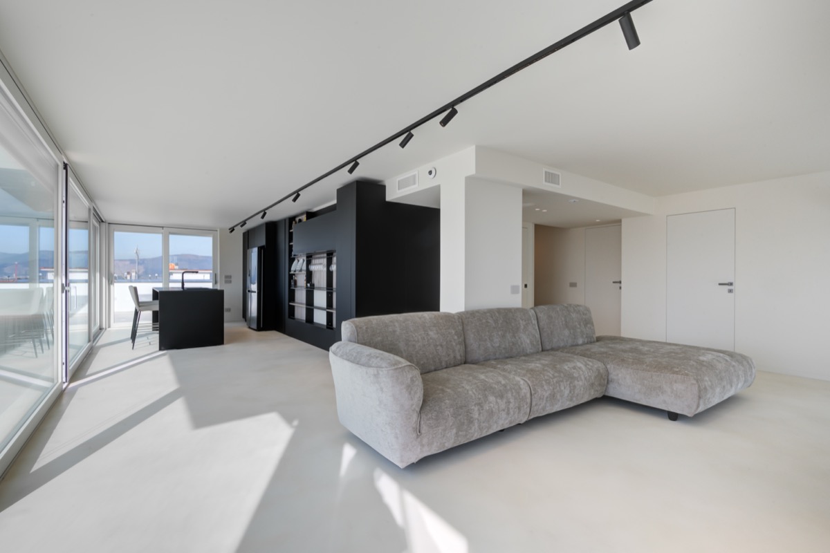 il secondo soggiorno con divano Edra e la cucina a isola nera. Nello stesso interno il camino bifacciale in travertino